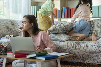 Young woman using mobile phone while sitting on sofa