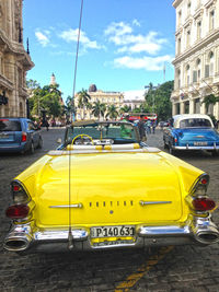 Yellow car on street against buildings in city