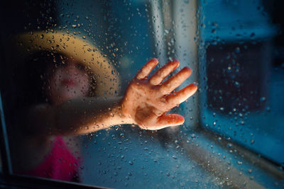 Low section of man seen through wet glass