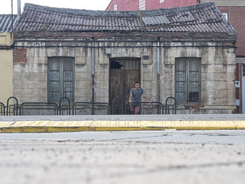 Young man standing against old house