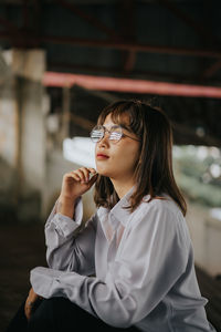 Young woman looking away while standing outdoors