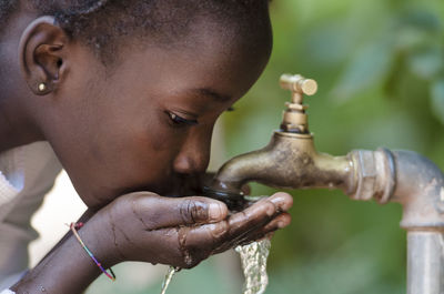 Girl drinking water from faucet