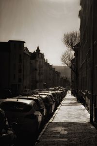 Cars on street by buildings against sky in city