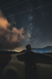 Side view of man standing against sky at night