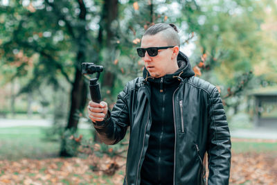Young man wearing sunglasses standing against trees