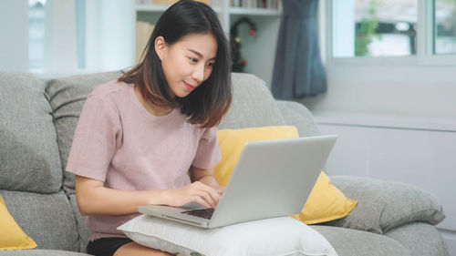 Young woman using mobile phone at home