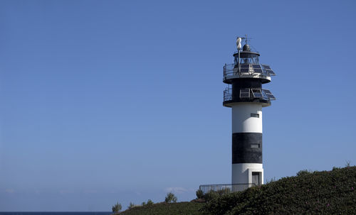 Lighthouse by sea against clear sky