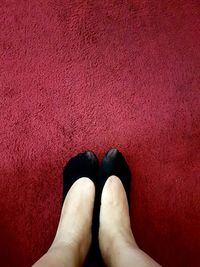 Low section of woman wearing socks while standing on carpet