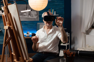 Senior man wearing virtual reality simulator sitting on chair