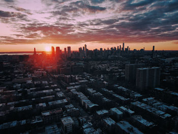 Aerial view of city buildings against sky during sunset