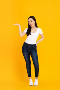 Portrait of a smiling young woman against yellow background