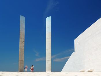 People at beach against clear blue sky