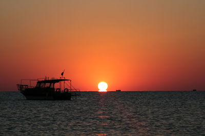 Boats in calm sea at sunset