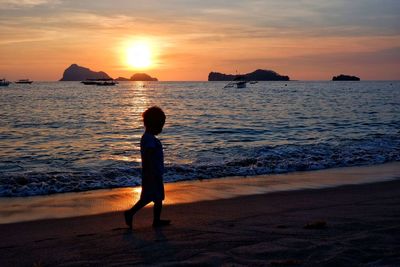 Silhouette man standing on beach against sky during sunset