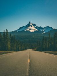 Road by mountains against clear sky