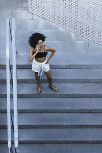 Young woman using smart phone while standing on steps