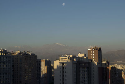 Buildings in city against clear sky at dusk