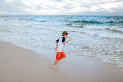 Full length of boy on beach against sky