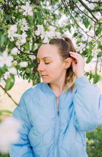 Portrait of young woman standing against trees