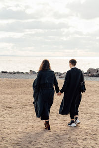 Rear view of women on beach against sky