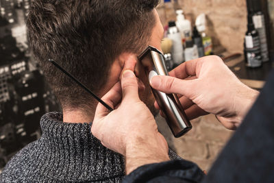 Cropped hands of barber trimming beards of man