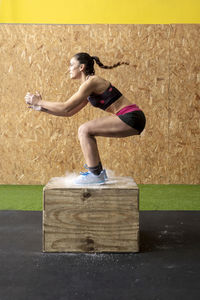 Fit woman jumping on a gym box for workout