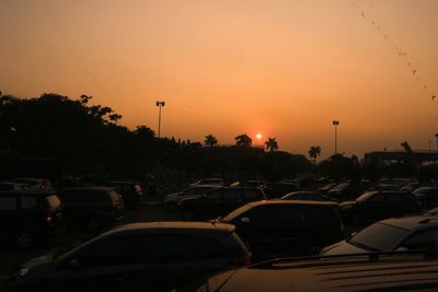 Cars on city against sky during sunset