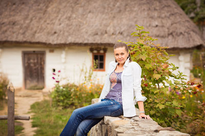 Young pretty ukrainian woman sitting near old rural countryside house