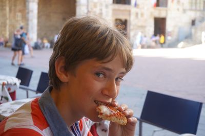 Portrait of boy eating pizza in restaurant