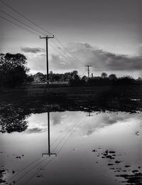 Electricity pylon by trees against sky