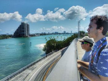 Man on bridge against sky in city