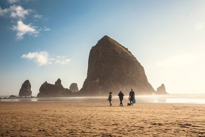 People on beach against sky during sunset