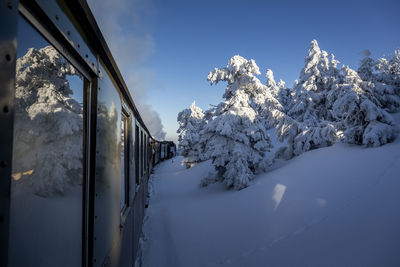 Train on snow covered field against sky