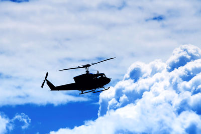 Silhouette helicopter flying in cloudy sky