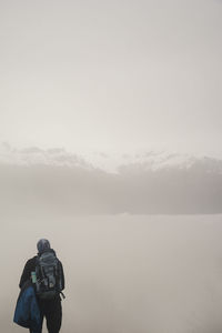 Rear view of man standing against mountains and sky