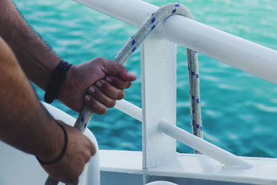 Close-up of hand holding rope in sea