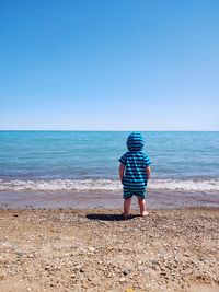 Rear view of man on beach against clear sky