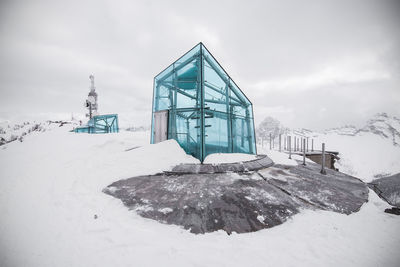Frozen built structure against sky during winter