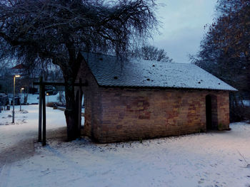 House on snow covered field against sky