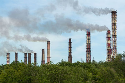 Smoke emitting from factory against sky