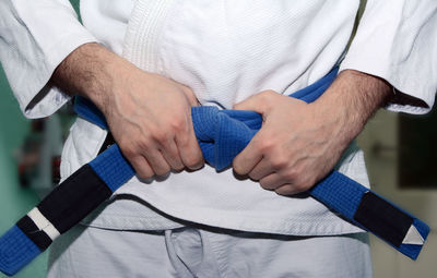 Midsection of man wearing belt while practicing karate