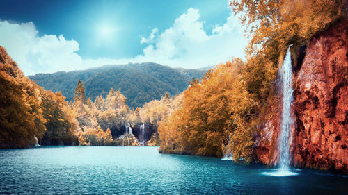 Scenic view of waterfall against sky during autumn