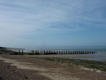 Scenic view of calm beach against cloudy sky