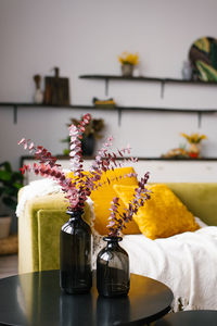 Stylish interior of room with sofa and eucalyptus branches in vase on table