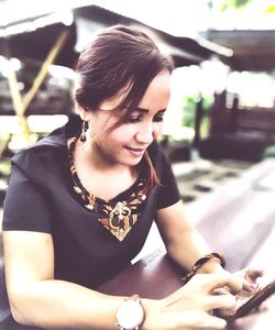 Young woman looking down while sitting outdoors