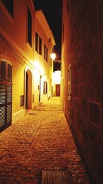 Walkway amidst buildings at night