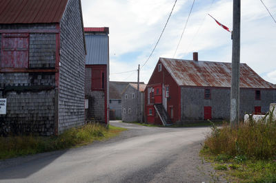 Road by buildings against sky in city