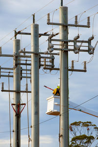 Low angle view of man sitting on pole against sky