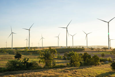 Wind turbines on field against sky