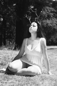 Young woman wearing antler on grassy field